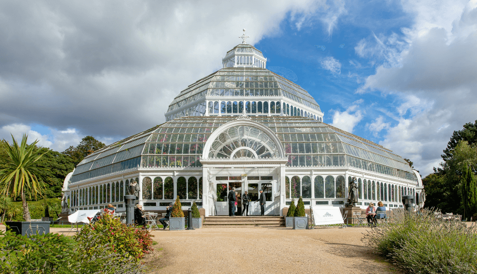 A large glass house in the middle of a park.