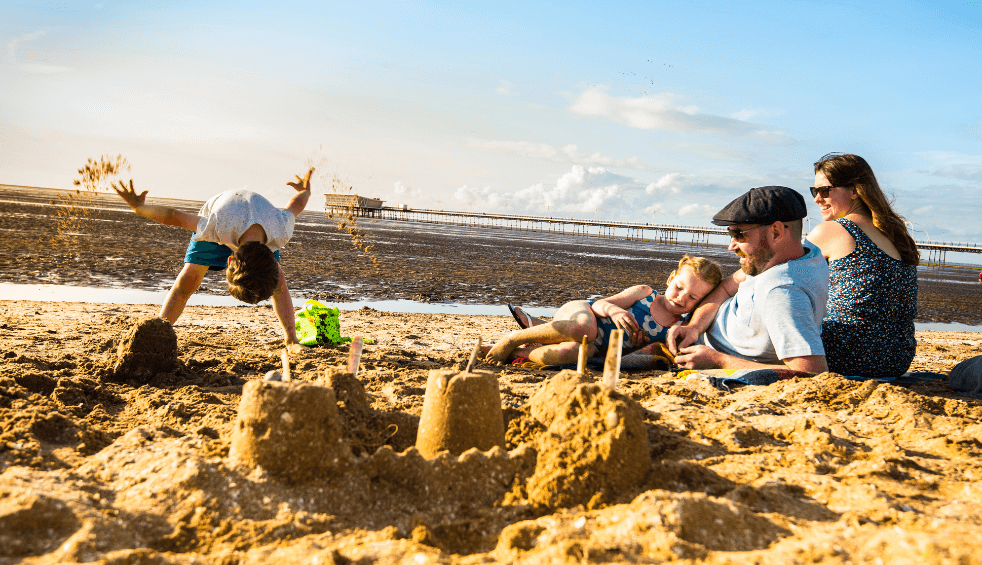 A family on the beach playing in the sandcastles on a sunny day