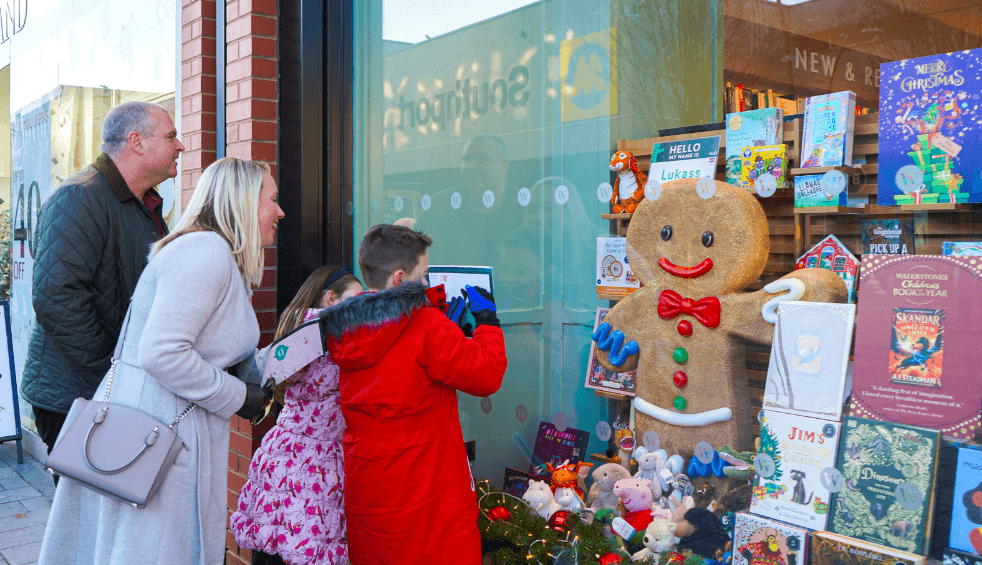 A family looking into a window with a giant gingerbread man.