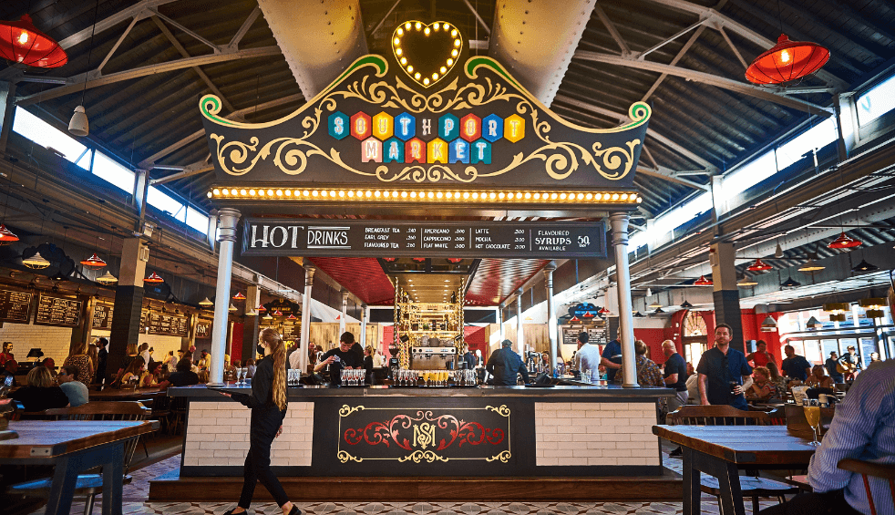 Inside southport Market with a food stall.