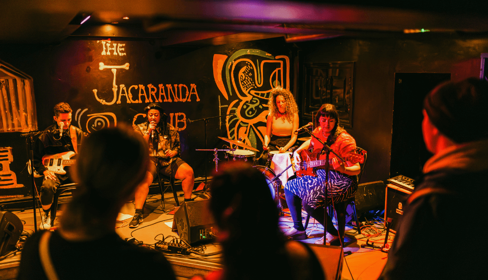 Inside the Jacaranda with a band on a stage and crowd.
