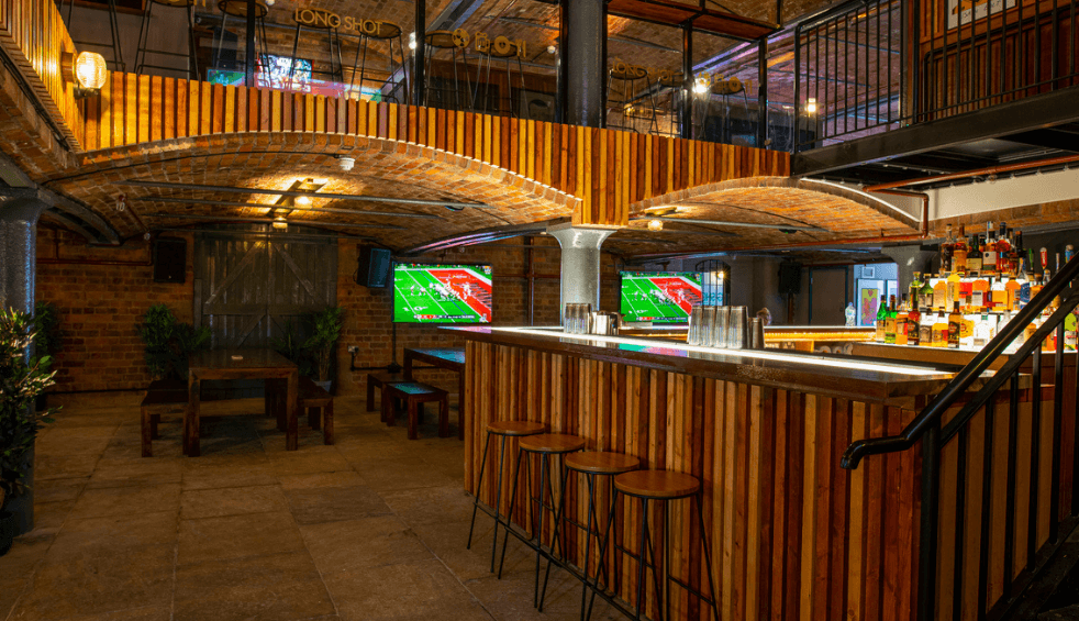 Inside a bar with a wooden bar and tvs on the wall.