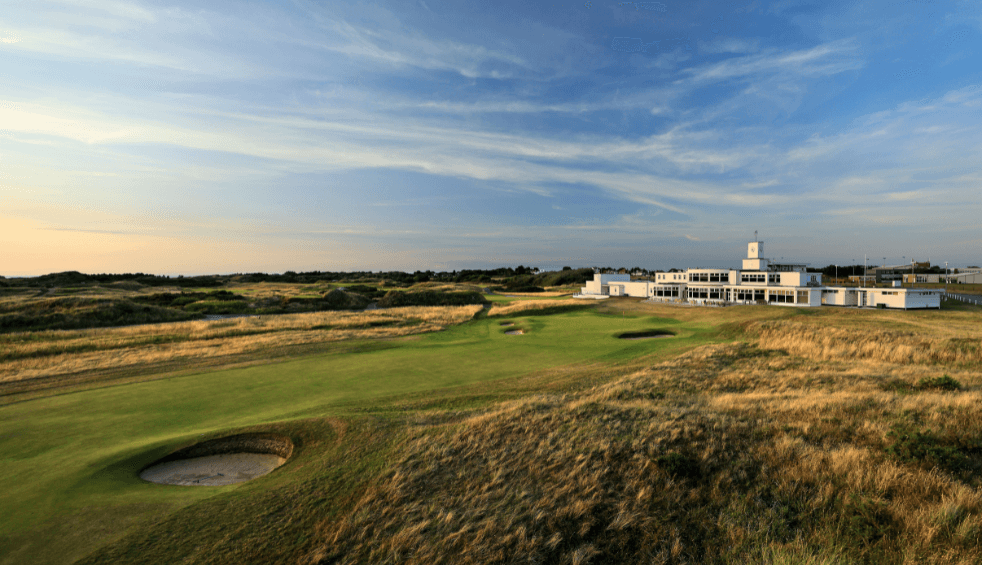 The Royal Birkdale golf club at the end of a gold course with green grass and grassy bunkers.