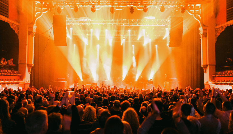 Inside the Olympia music venue with a large crowd and orange lights from the stage.