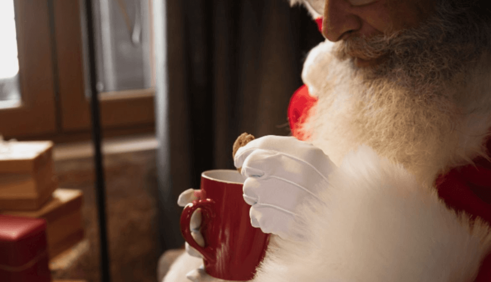 Santa dunks a biscuit into a mug.