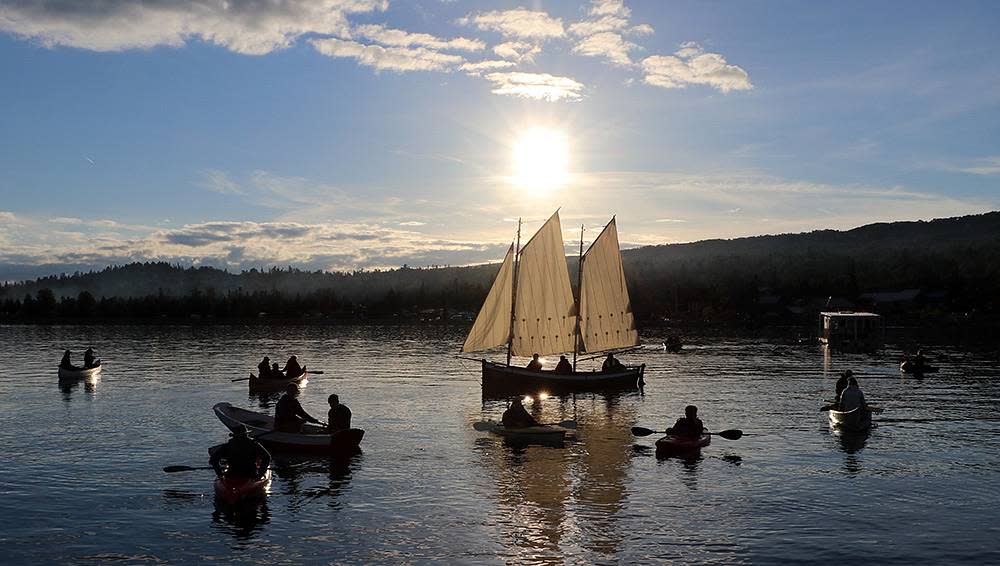 A group of boaters and sailors on a lake.