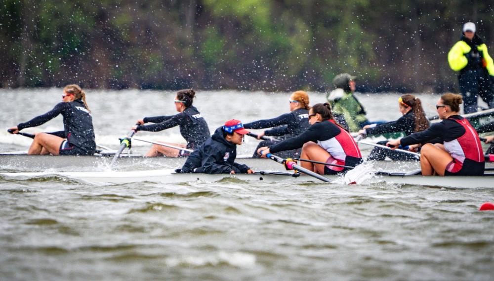 competitive rowing on Ford Lake. Women's team paddling across lake as coaches encourage rowing.