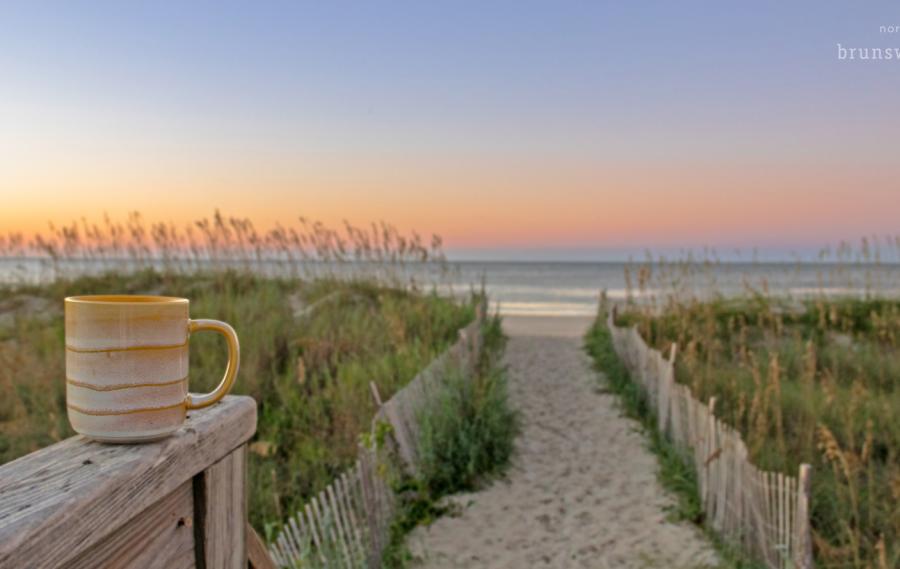 Coffee cup on beach path at sunrise