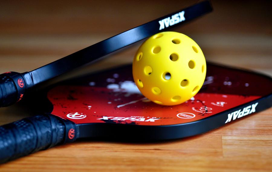 A ball between two pickleball racquets