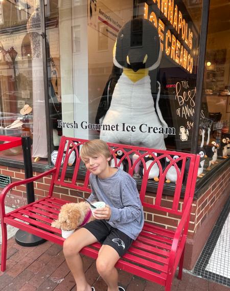 A boy and his dog sitting on a bench eating ice cream