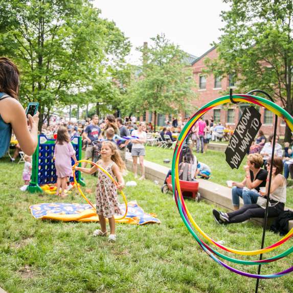 A mom taking a photo of her daughter hoola hooping at Taste of Bloomington