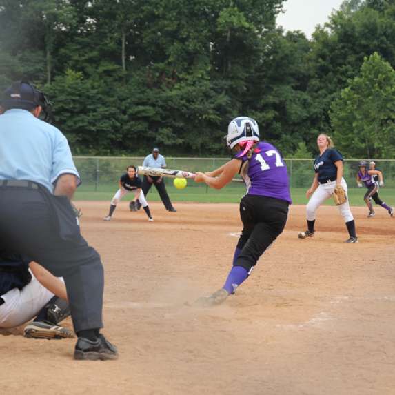 A batter hitting a softball during a game