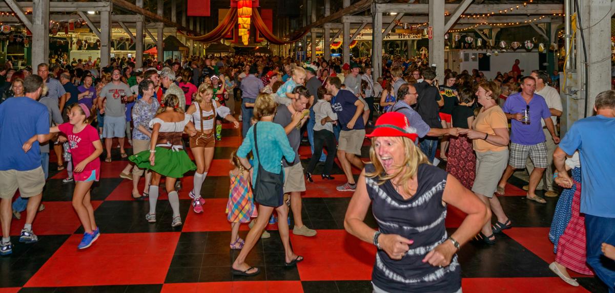 Dancing crowd in leiderhosen and traditional German hats at Columbus Oktoberfest