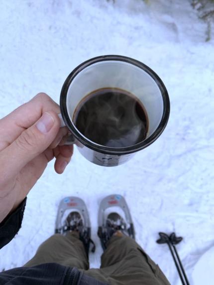 Snowshoeing while holding a cup of coffee.