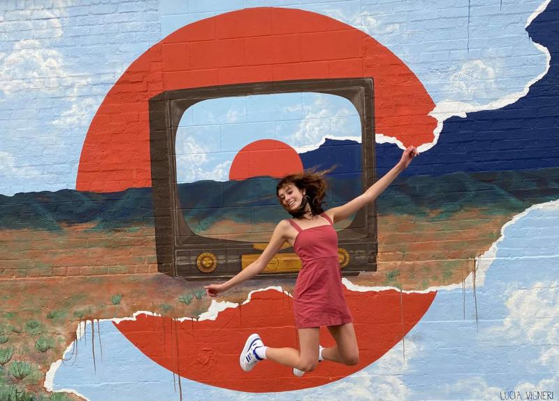 A woman posing in front of the Lucia Vigneri Mural in Casper, WY