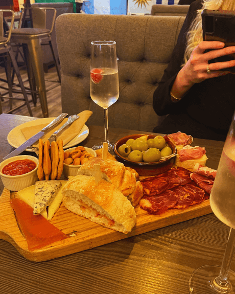 A board of meat, cheeses, olives and prosecco