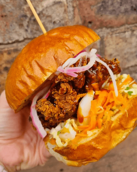 A burger with pink onions in a brioche bun
