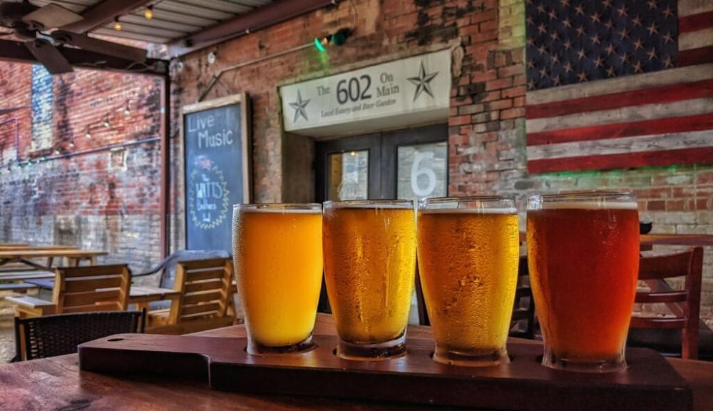 A row of glasses full of different types of beer.