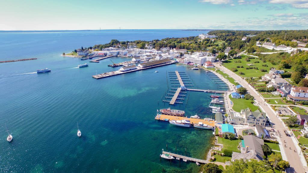 An aerial drone perspective of the Mackinac Island marina and downtown buildings on a sunny summer day