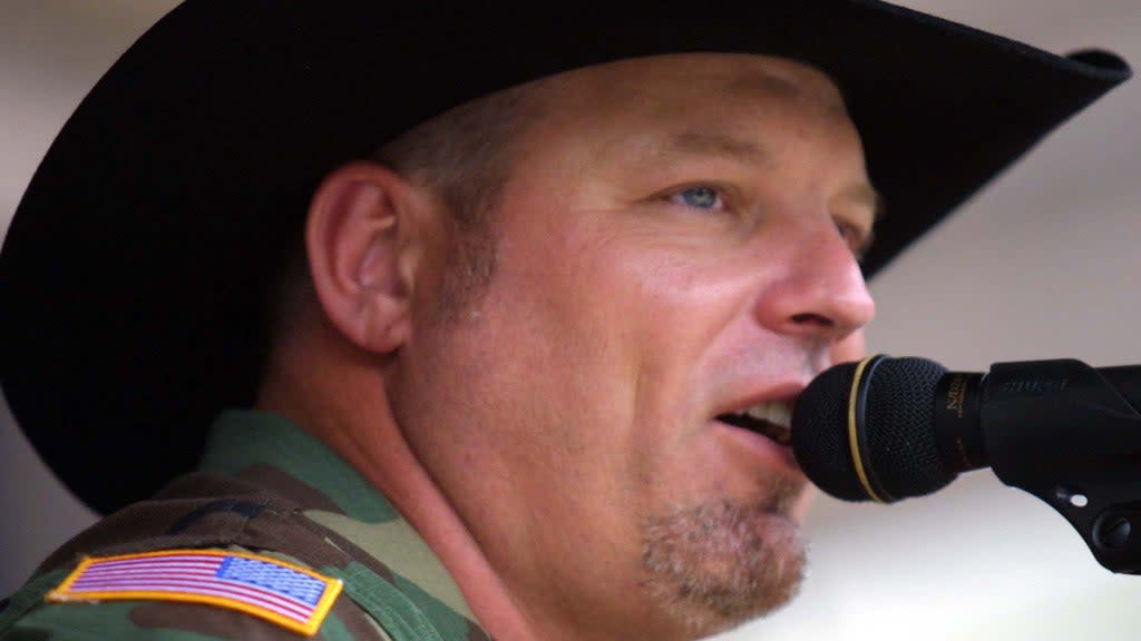 Country singer John Michael Montgomery sings into a mic during a concert