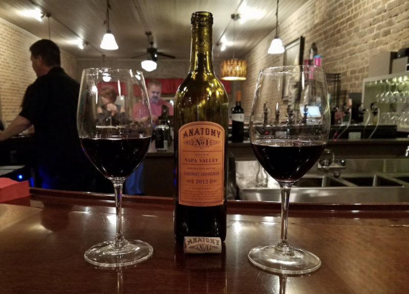 two glasses of wine surrounding a bottle of wine
