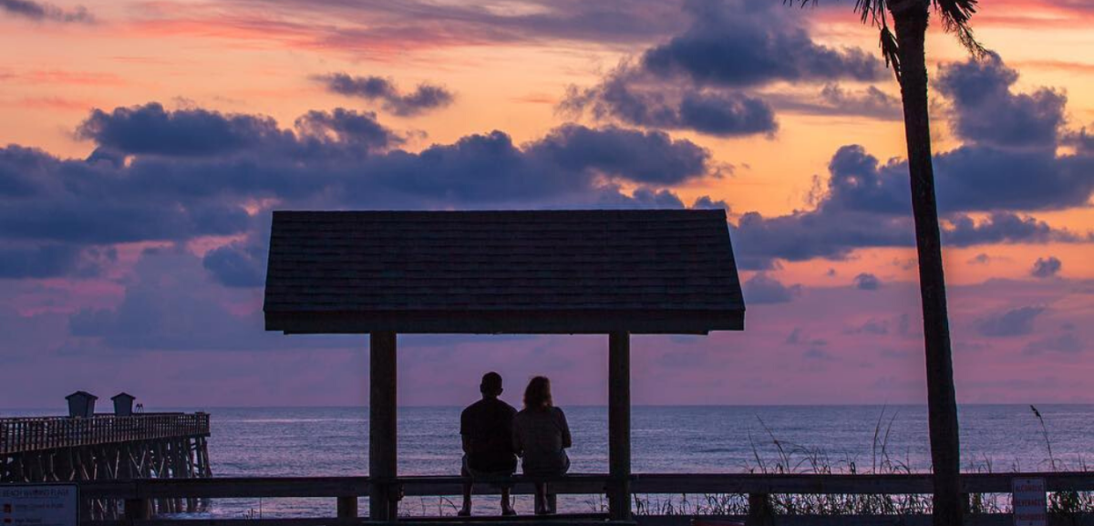 couple sitting at flagler beach at dusk