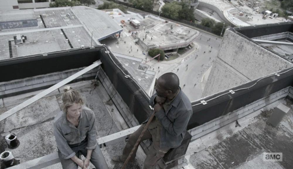 Fear the Walking Dead screengrab showing zombies walking around the outside of an old Hospital during the day