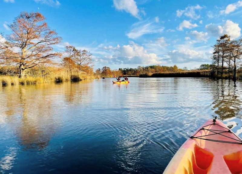 view of open fresh water from kayaker's perspective with another kayaker in view in the distance