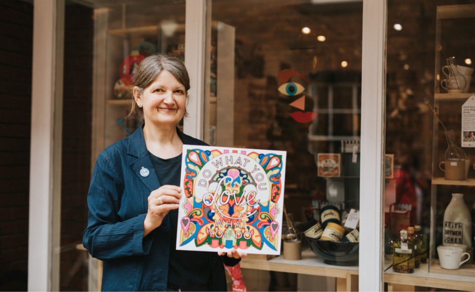 A woman holding an item in front of her store.