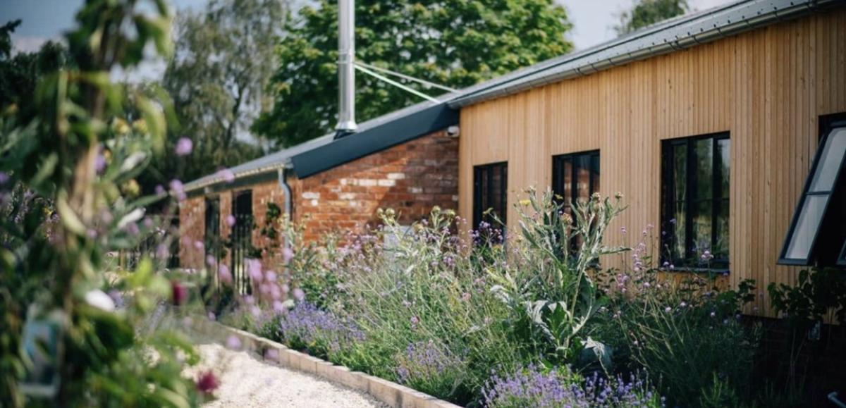A path, a storehouse and some wild flowers growing at The Farm