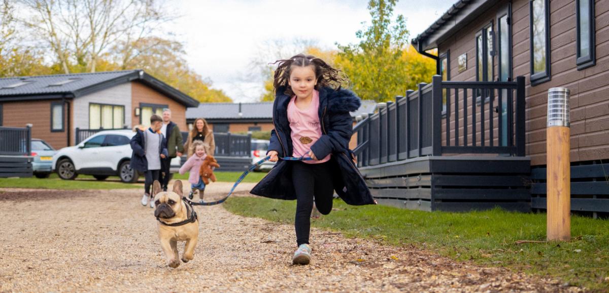 Girl running with her dog at holiday park in the New Forest