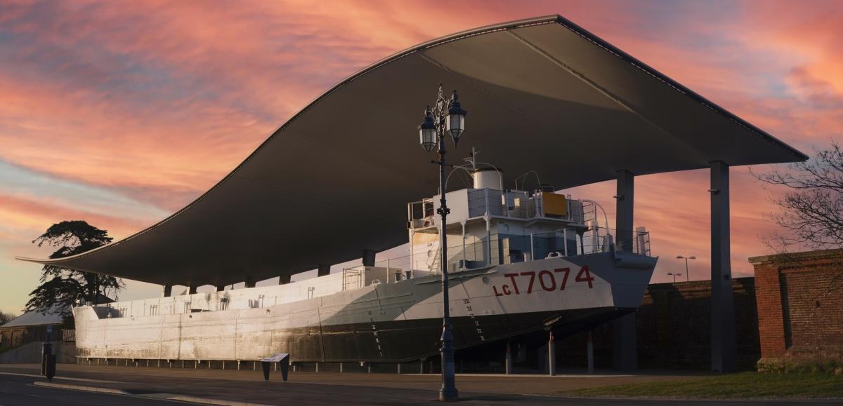 Photograph of LCT 7074 outside The D-Day Story, under a vibrant pink sky