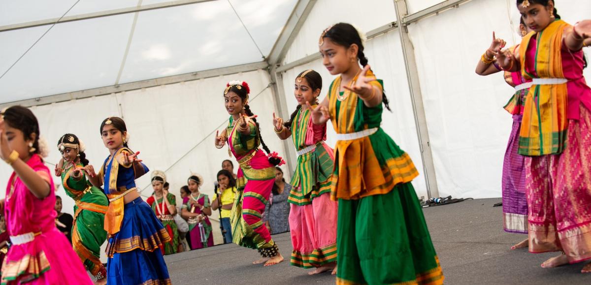 Group of young women, dressed in colourful attire, performing traditional dance at the Southampton Mela Festival
