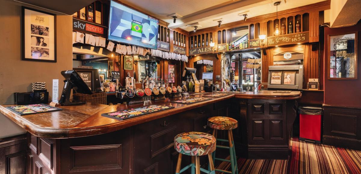 Inside of The Grapes pub and accommodation. Shot of an empty bar with stools and taps.