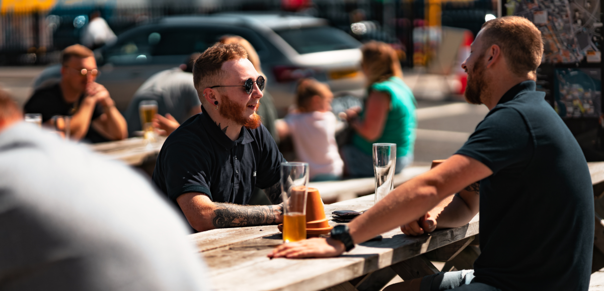 Two people drinking outside Dancing Man Brewery
