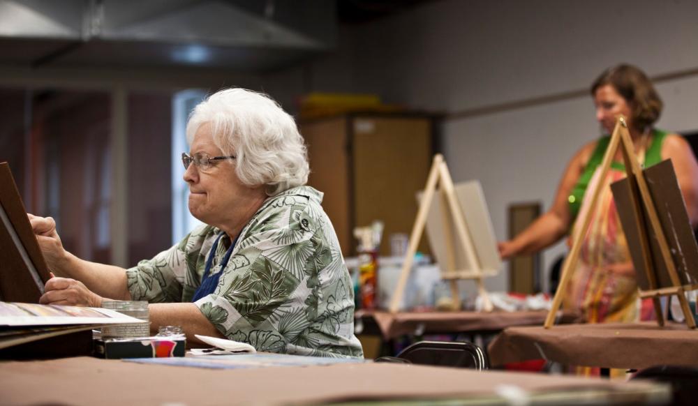 An elderly woman focuses on her painting at CityArts in Wichita