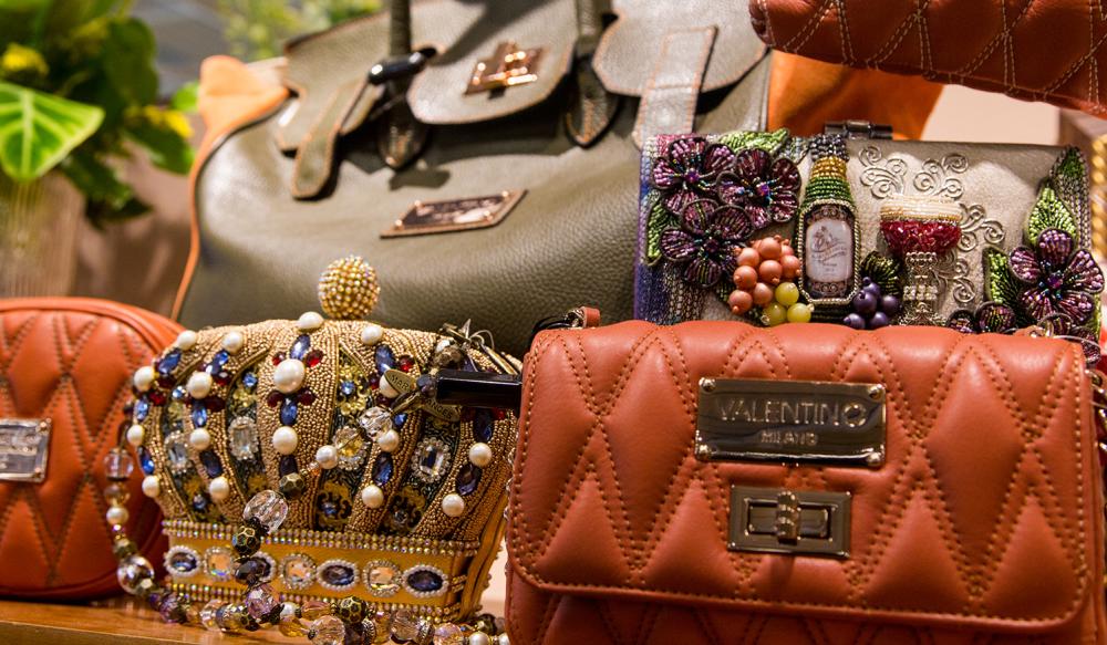 A Valentino hand bag and several other purses on a table
