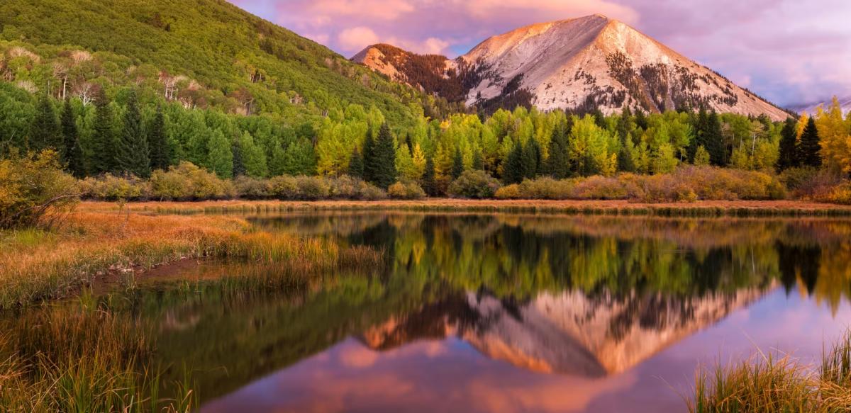 A scenic view of the tranquil reflection of an autumn sunset over Warner Lake in the La Sal Mountains, part of the Manti-La Sal National Forest near Moab, Utah.