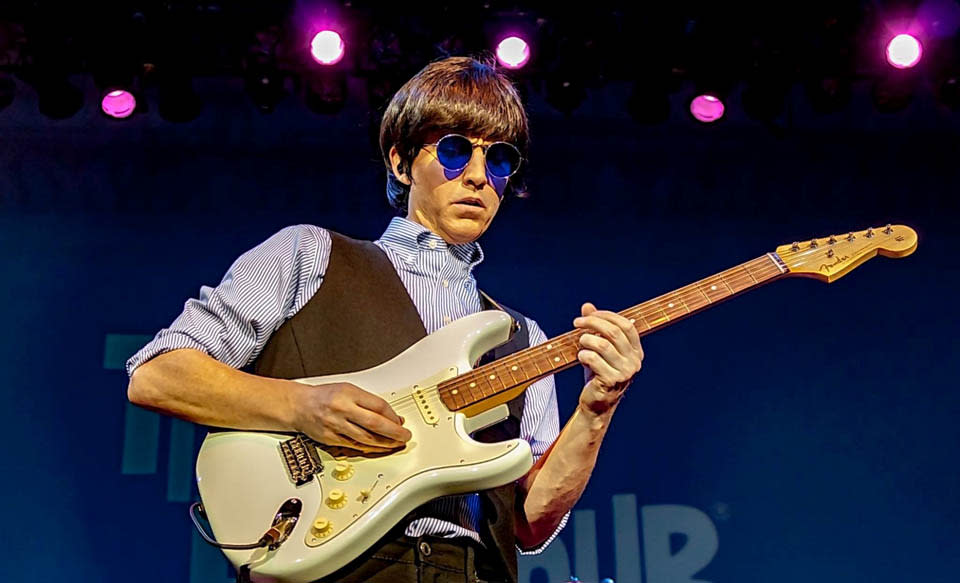 artist playing guitar on stage