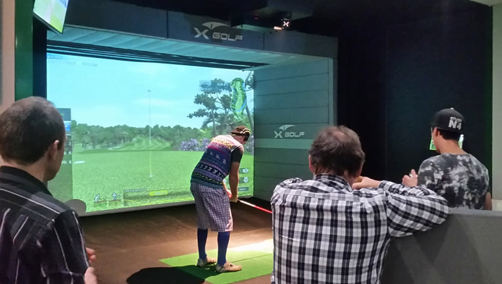 Friends watch as man tees up indoors at X-Golf in Lafayette, LA