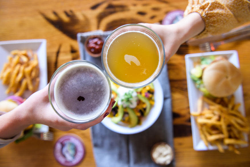 People holding two beers with meals as the backdrop at Tarpon Brewery