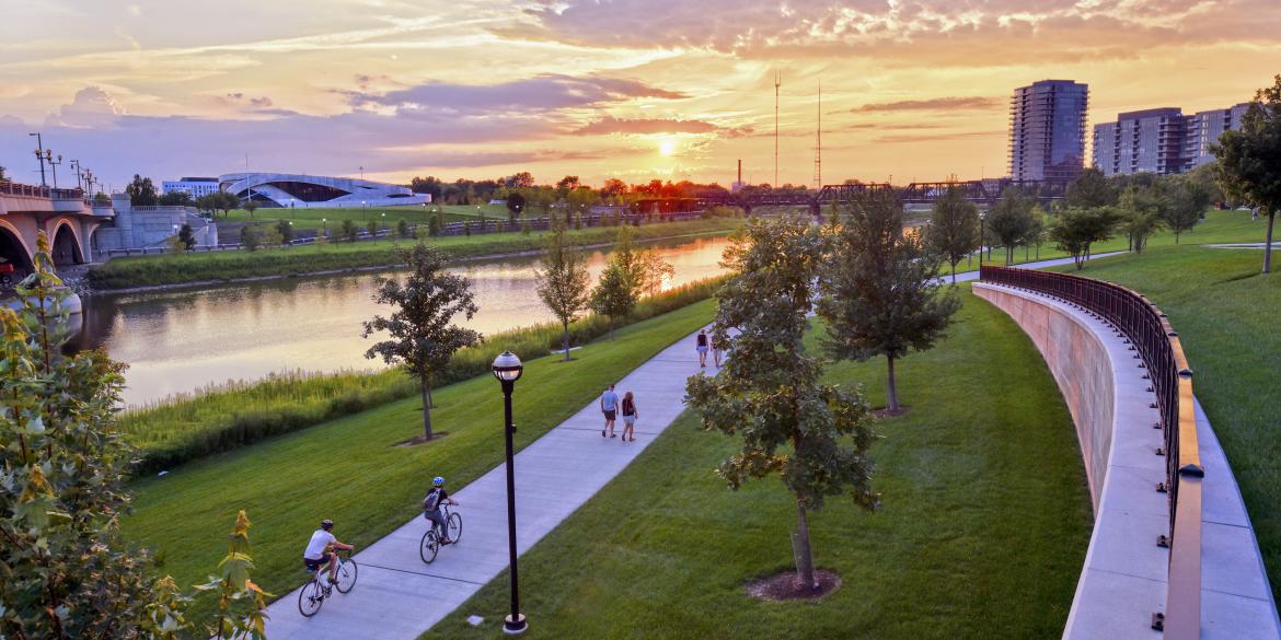 Aerial view of people riding bikes on path along river during sunset at the Scioto Mile