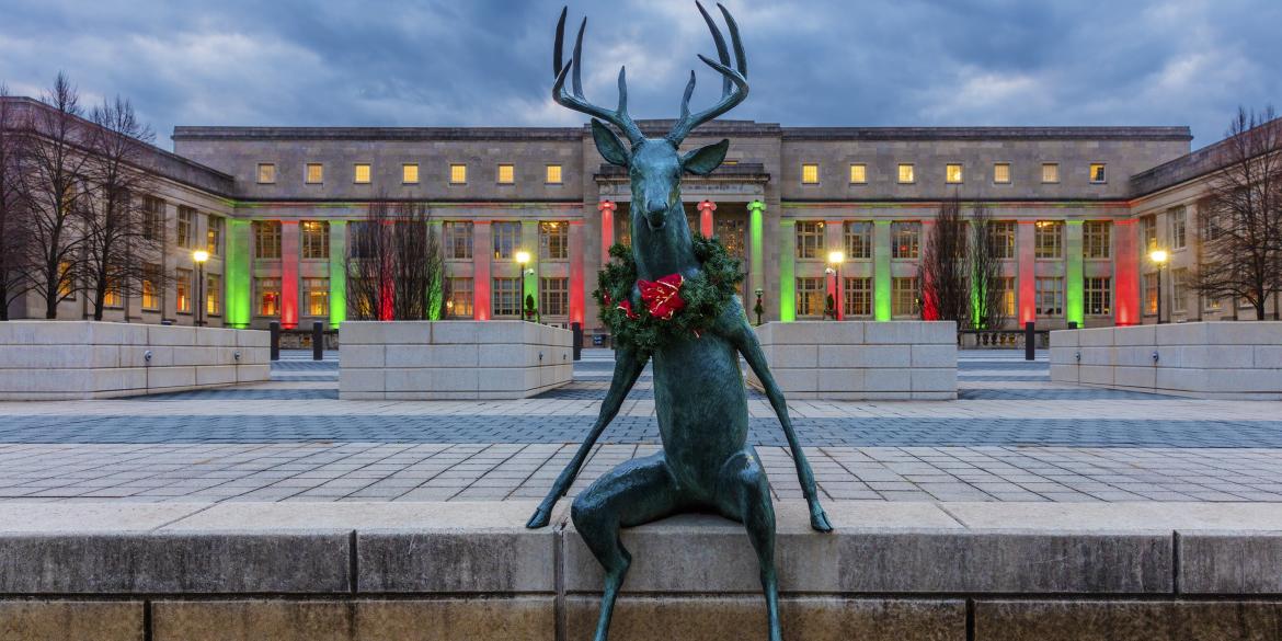 Scioto Mile deer sculpture decked for the holidays with wreath in front of COSI lit with festive holiday lights