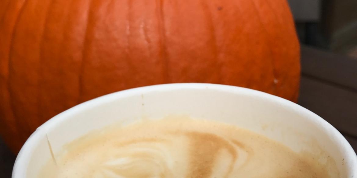 Close-up of pumpkin coffee with foam standing in front of pumpkin