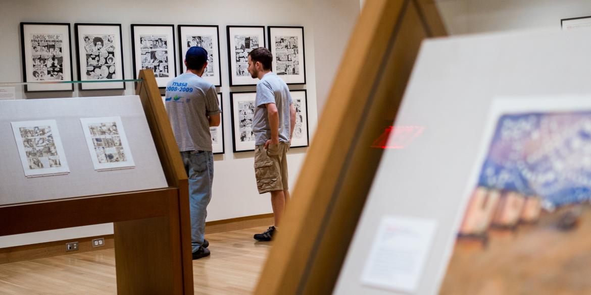 Close up of artwork with patrons in background at the Billy Ireland Cartoon Museum