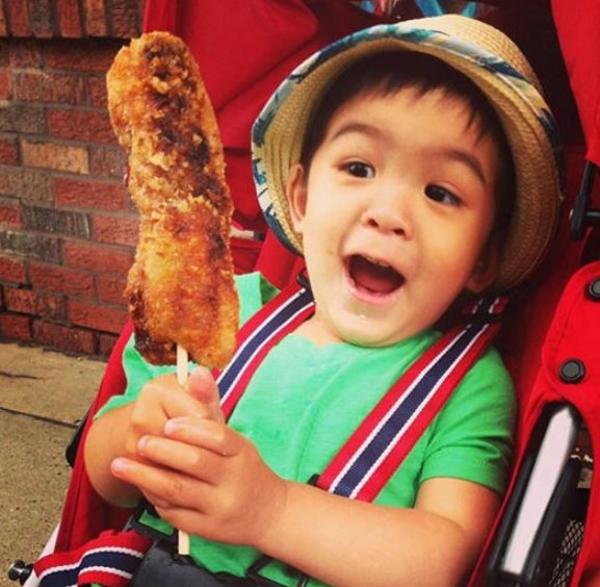 Child holding a giant egg roll on a stick