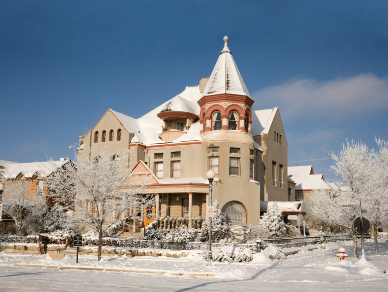 Historic Nagle Warren Mansion covered in snow, a charming hotel for a romantic weekend in Cheyenne.