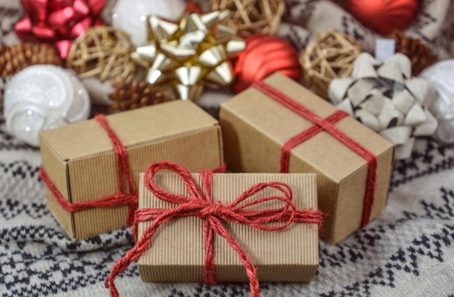 Three simply wrapped packages with bows and ornaments in the background