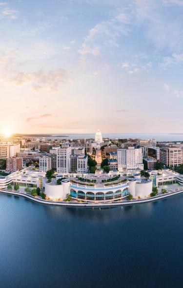 A panoramic view of a vibrant city skyline along a waterfront at sunrise, showcasing modern buildings and lush greenery.