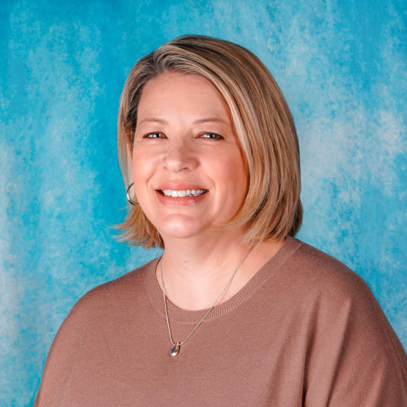 Woman's professional headshot on a blue background.